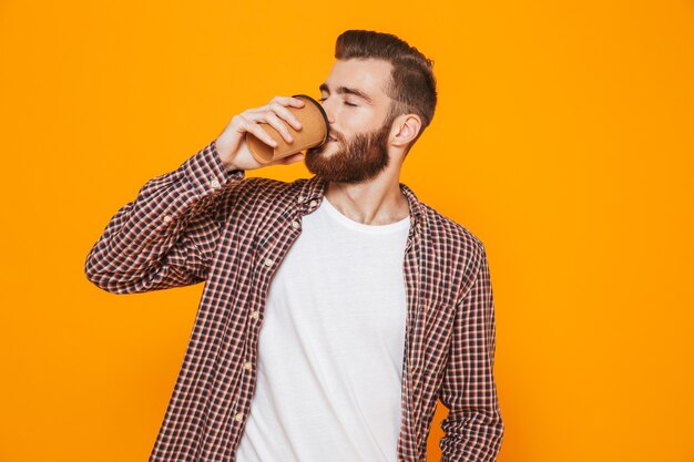 Ritratto di un giovane felice che indossa abiti casual in possesso di caffè da asporto