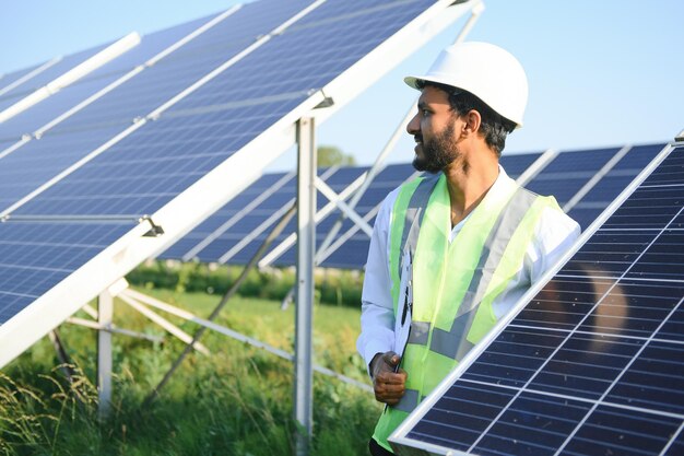 Ritratto di un giovane ingegnere indiano in piedi vicino a pannelli solari con sfondo blu limpido Energia rinnovabile e pulita Skill India copy space