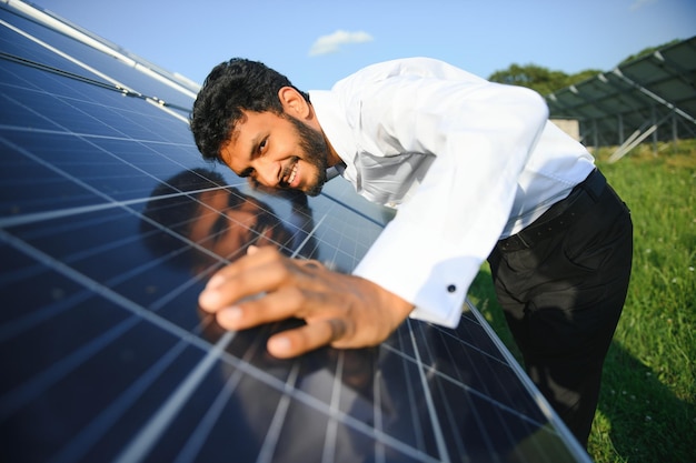 Ritratto di un giovane ingegnere indiano in piedi vicino a pannelli solari con sfondo blu limpido Energia rinnovabile e pulita Skill India copy space