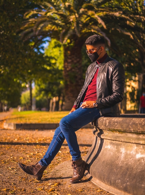 Ritratto di un giovane latino in città presso una fontana. Jeans, giacca di pelle e scarpe marroni