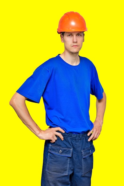 Ritratto di un giovane lavoratore magro in un casco da costruzione e una maglietta blu Un costruttore o appaltatore