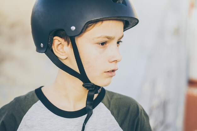 Ritratto di un giovane pattinatore alla moda allo skatepark con il casco che guarda via un adolescente che si diverte all'aperto