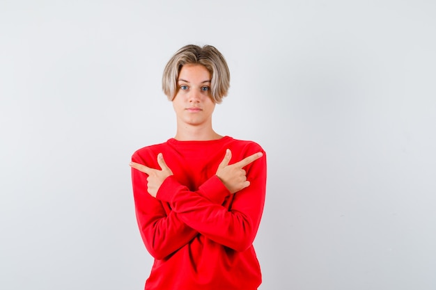 Ritratto di un giovane ragazzo adolescente che punta a sinistra e a destra con un maglione rosso e sembra fiducioso in vista frontale