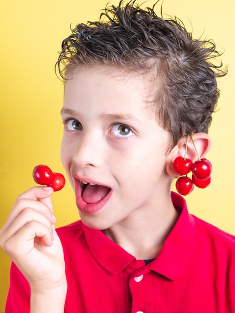 Ritratto di un giovane ragazzo con orecchini di ciliegie fresche