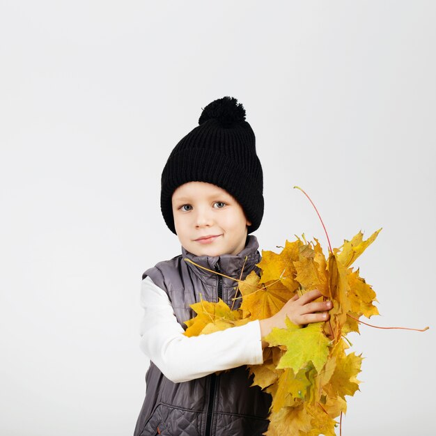 Ritratto di un giovane ragazzo in possesso di foglie di autunno