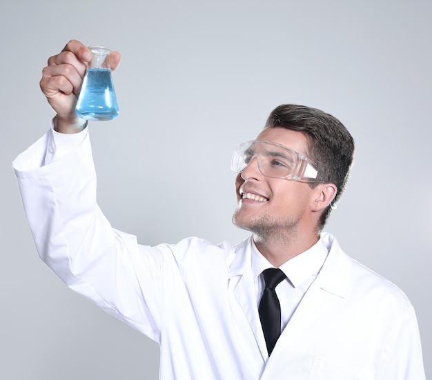 Ritratto di un giovane scienziato maschio allegro vestito in uniforme che mostra provette isolate su sfondo bianco