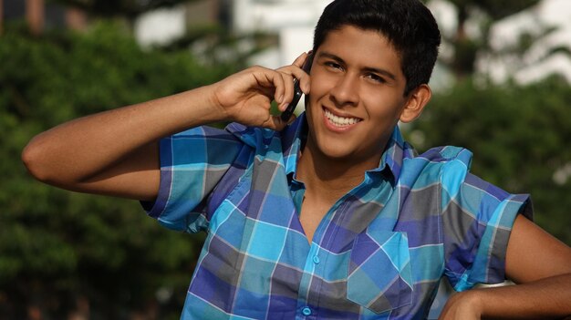 Ritratto di un giovane sorridente che parla al cellulare mentre si trova all'aperto