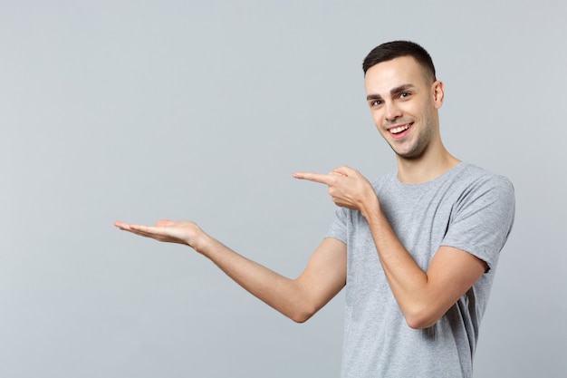 Ritratto di un giovane sorridente in abiti casual, che punta il dito indice, mano da parte