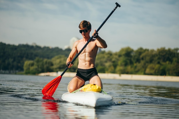 Ritratto di un giovane sportivo che rema sull'acqua su una tavola da sup