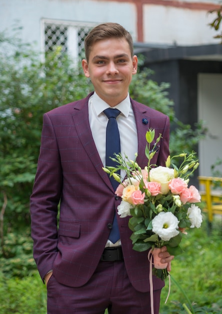 ritratto di un giovane sposo con un bouquet il giorno del matrimonio