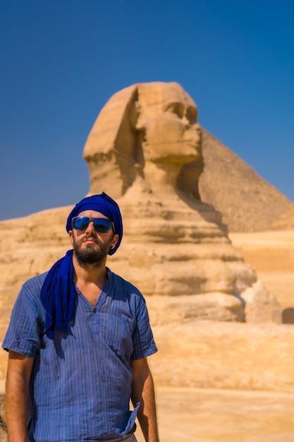 Ritratto di un giovane turista vestito di blu e un turbante blu presso la Grande Sfinge di Giza. Cairo, Egitto