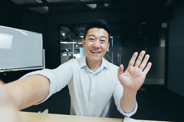 Ritratto di un giovane uomo asiatico bello che prende un selfie registrando un video che parla durante una videochiamata