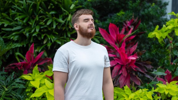 Ritratto di un giovane uomo barbuto felice con la barba che respira profondamente l'aria fresca sullo sfondo naturale