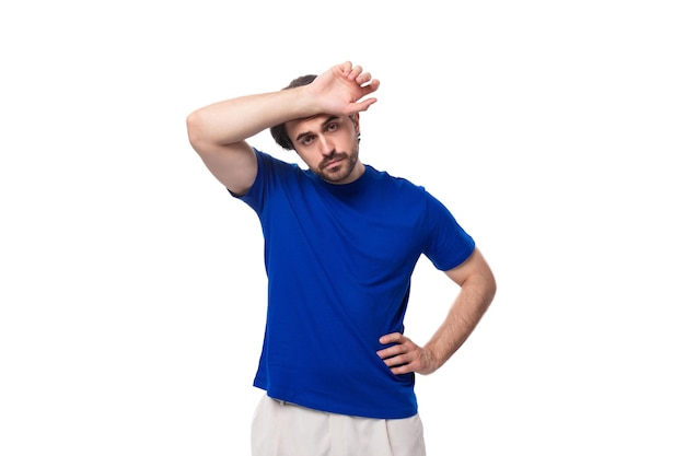 Ritratto di un giovane uomo brunetto caucasico intelligente con la barba in una maglietta blu che pensa