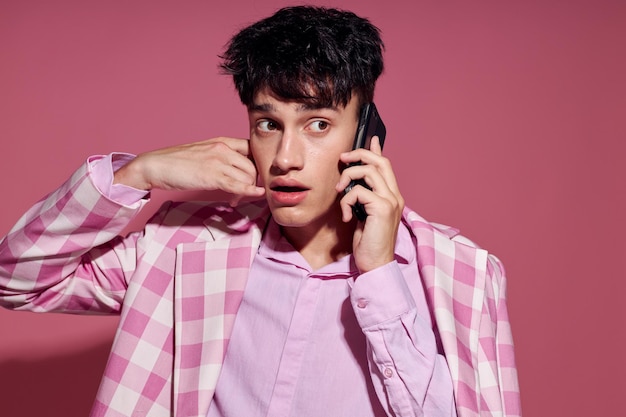 Ritratto di un giovane uomo con un telefono in mano blazer rosa moda stile elegante stile di vita inalterato