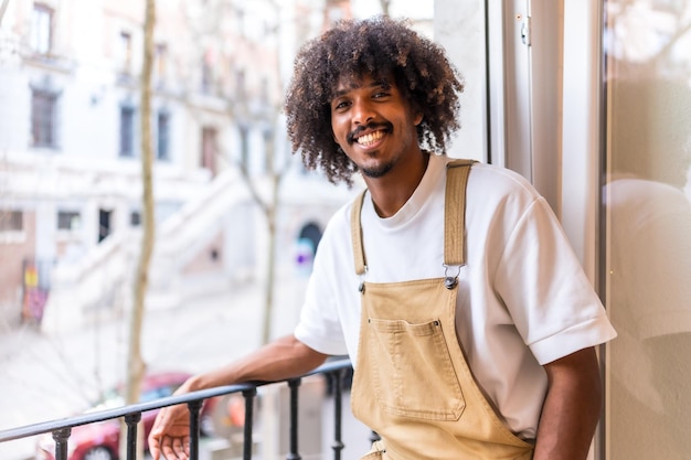 Ritratto di un giovane uomo etnico nero su un balcone a casa situazione quotidiana appartamento sorridente