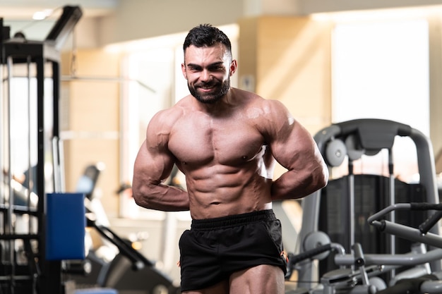 Ritratto di un giovane uomo fisicamente in forma che mostra il suo corpo ben allenato modello di fitness bodybuilder atletico muscolare in posa dopo gli esercizi