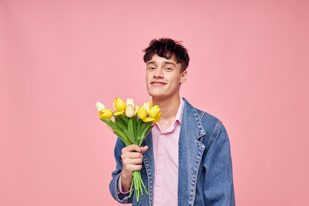 Ritratto di un giovane uomo in una giacca di jeans con un mazzo di fiori un regalo romantico vacanza inalterato