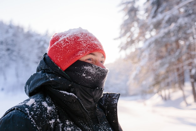 Ritratto di un giovane uomo in una soleggiata giornata invernale sullo sfondo di una foresta innevata