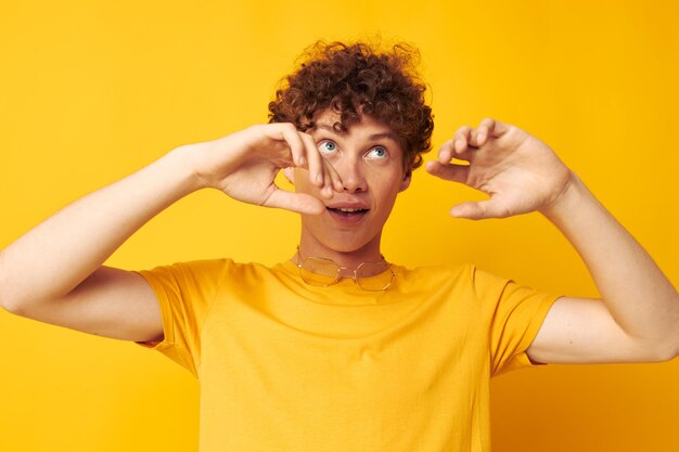 Ritratto di un giovane uomo riccio giallo maglietta occhiali moda gesti della mano colpo monocromatico