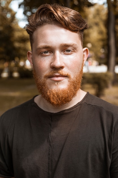 Ritratto di un giovane uomo rosso con barba e taglio di capelli alla moda