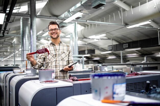 ritratto di un grafico professionista che controlla la produzione e la vernice su una moderna macchina da stampa