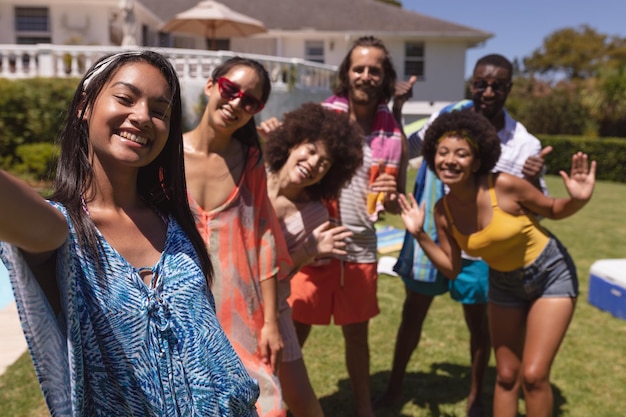 Ritratto di un gruppo eterogeneo di amici che prendono selfie a una festa in piscina. Uscire e rilassarsi all'aperto in estate.