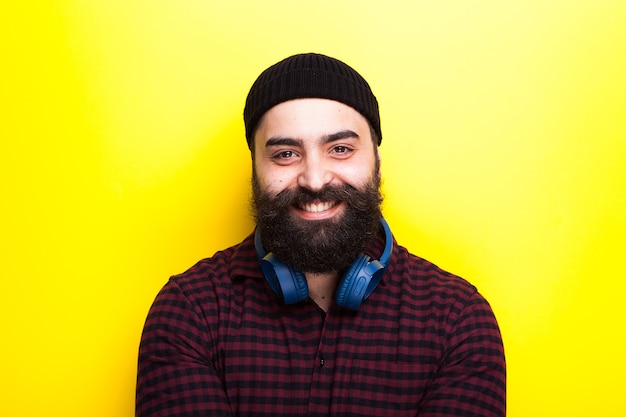 Ritratto di un hipster sorridente felice con una lunga barba su sfondo giallo