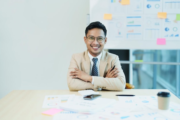 Ritratto di un imprenditore maschio che mostra una faccia sorridente felice mentre ha investito con successo la sua attività utilizzando computer e documenti di bilancio finanziario al lavoro