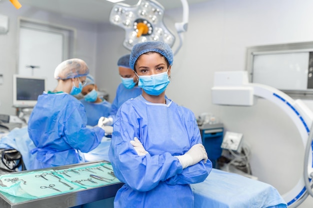 Ritratto di un'infermiera donna chirurgo o membro dello staff vestito con abiti chirurgici maschera abito e rete per capelli in sala operatoria dell'ospedale che fa contatto visivo sorridendo soddisfatto felice guardando la telecamera