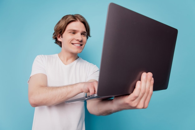 Ritratto di un influencer che tiene in mano un laptop che lavora isolato su sfondo blu
