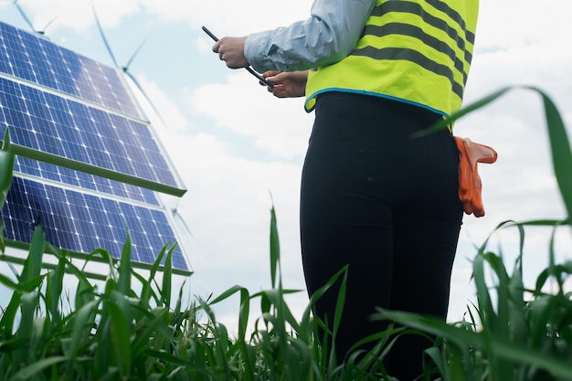 Ritratto di un ingegnere tecnico con un tablet in mano in piedi di fronte a un pannello solare esterno alto e incompiuto di una ragazza ingegnere tecnica di un sistema fotovoltaico