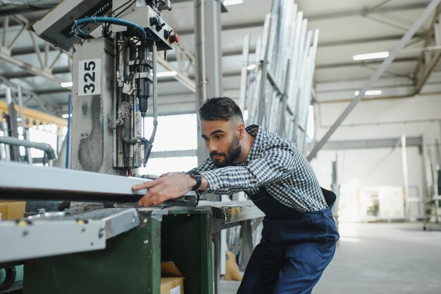 Ritratto di un lavoratore ingegnere professionista dell'industria pesante che indossa un cappello rigido uniforme di sicurezza sorridente sullo sfondo Grande fabbrica industriale sfocata