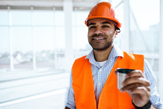 Ritratto di un lavoratore uomo in abiti da lavoro durante una pausa beve caffè e riposa