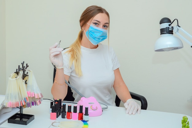 ritratto di un maestro di manicure nel salone sul posto di lavoro con gli strumenti nelle sue mani