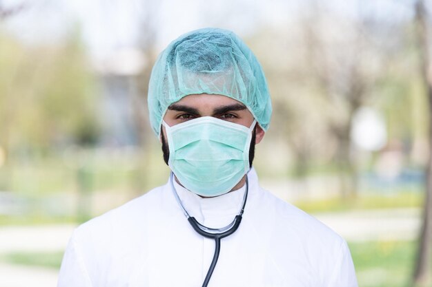 Ritratto di un medico caucasico maschio stanco esausto di fronte a un parco - Malattia da virus Coronavirus Covid-19 - Focolaio pandemico globale