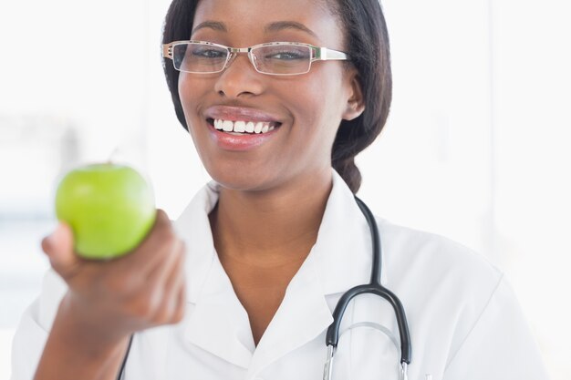 Ritratto di un medico femminile sorridente che tiene una mela