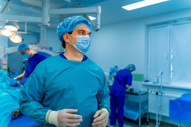 Ritratto di un medico o di un medico specialista Ritratto orizzontale Uomo in camice Sfondo della sala operatoria con luce blu Primo piano