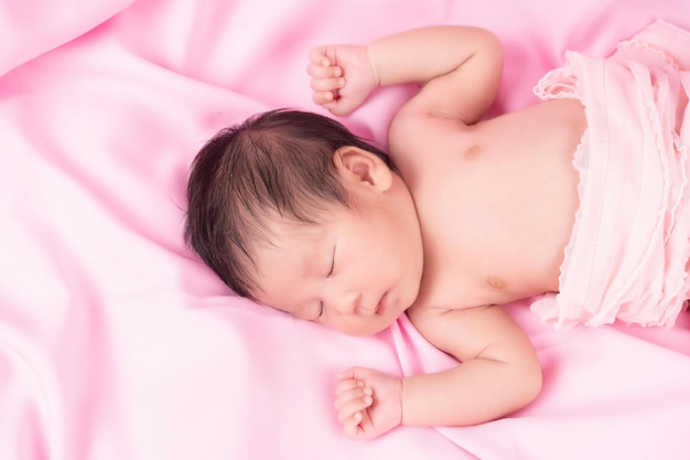 Ritratto di un mese di età che dorme, neonata su una coperta rosa. Concetto ritratto studio moda neonato.