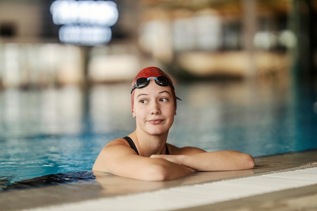 Ritratto di un nuotatore professionista appoggiato sul bordo della piscina e che fa una pausa