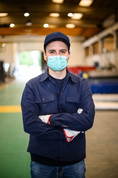 Ritratto di un operaio in uno stabilimento industriale che indossa una maschera, concetto di coronavirus