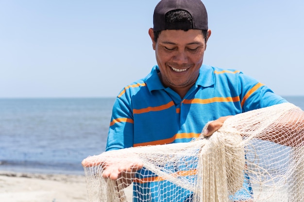 Ritratto di un pescatore sulla spiaggia Pescatore che fa manutenzione sulla sua attrezzatura da lavoro