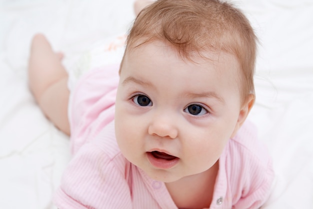 Ritratto di un piccolo bambino carino sdraiato sul suo stomaco, che sta imparando a gattonare