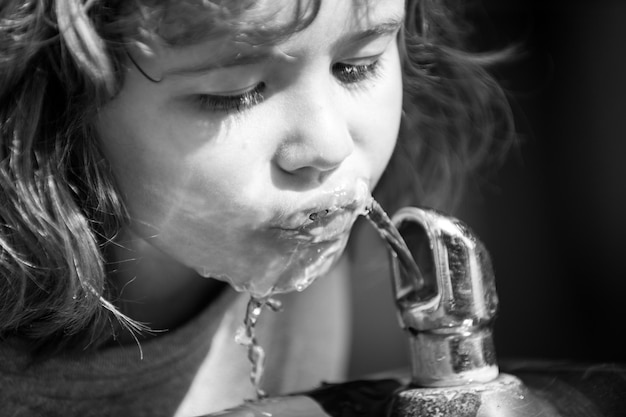 Ritratto di un piccolo ragazzo biondo che beve acqua all'aperto nel primo piano del parco Bambini carini faccia Bambino emotivo positivo Bambini assetati