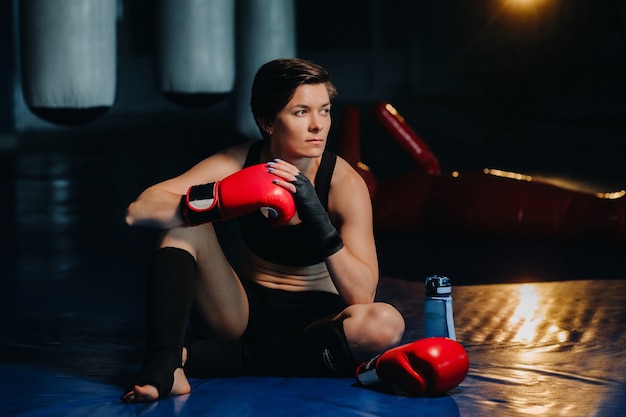 Ritratto di un pugile femminile in guanti rossi in palestra dopo l'allenamento