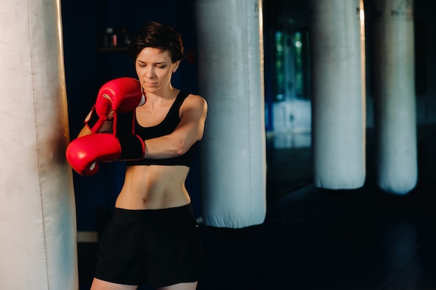 Ritratto di un pugile femminile in guanti rossi in palestra durante l'allenamento