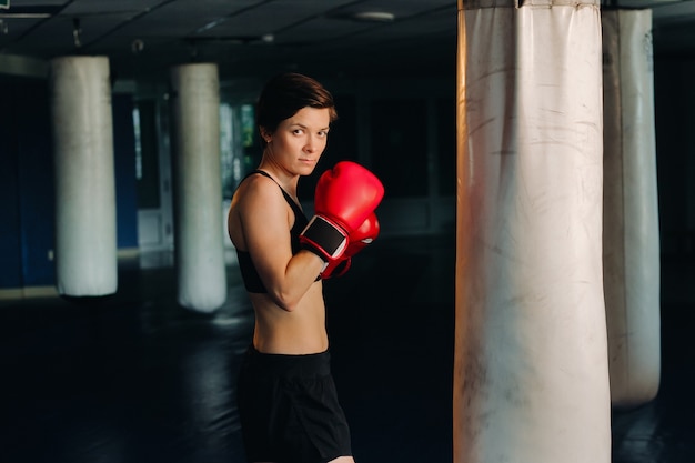 Ritratto di un pugile femminile in guanti rossi in palestra durante l'allenamento