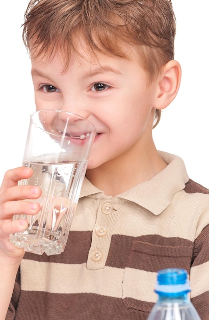 Ritratto di un ragazzino allegro con una bottiglia di vetro e plastica d'acqua Un bambino sorridente e carino beve acqua isolato su uno sfondo bianco