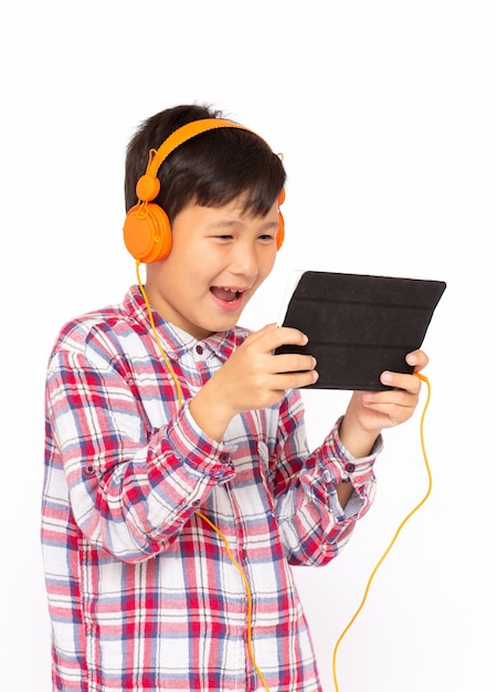 Ritratto di un ragazzino che gioca al tablet e indossa le cuffie su sfondo bianco