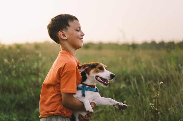 Ritratto di un ragazzino che gioca con il suo cane Jack Russell nel parco Concetto di animali amicizia persone e amore Un ragazzo gioca con un Jack Russell terrier